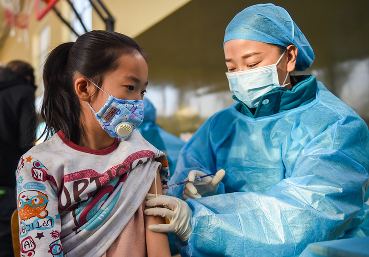 11月23日,在呼和浩特市回民区实验小学,医务人员为学生接种疫苗.